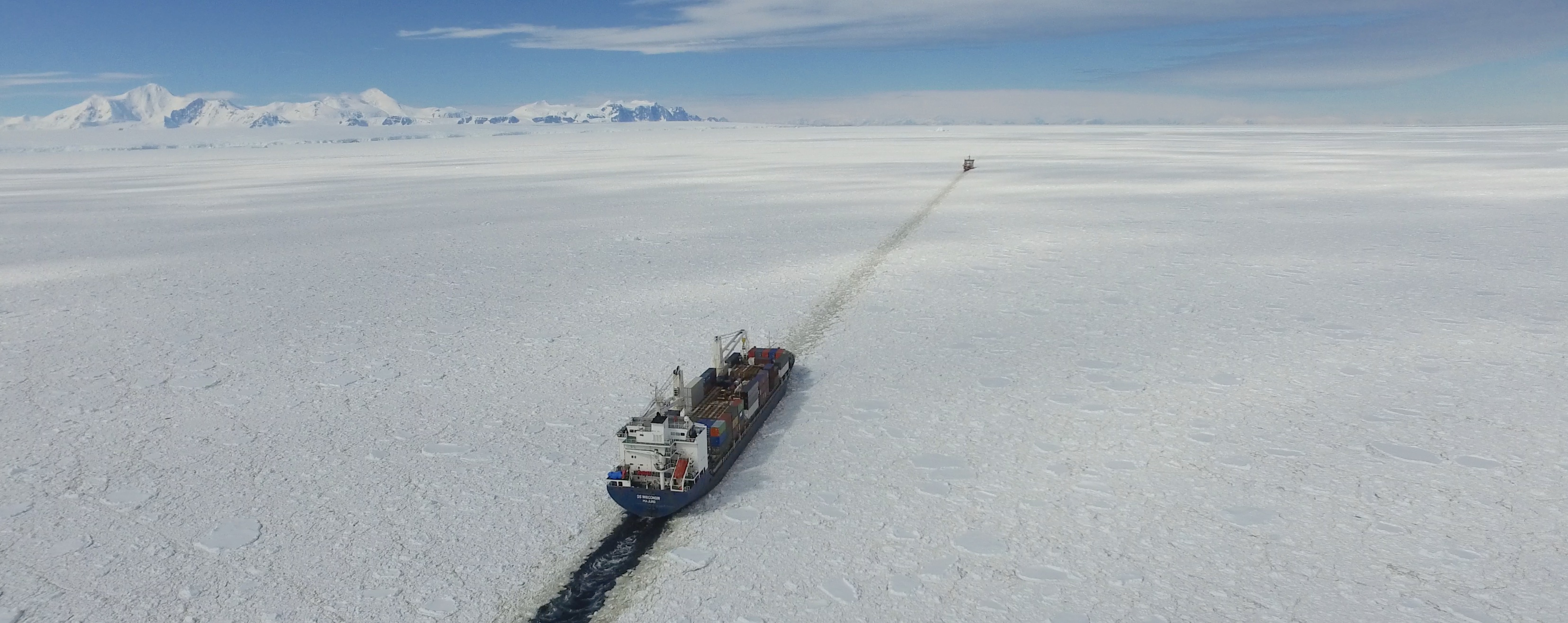 A container ship being escorted through ice by an icebreaker in the Antarctic.